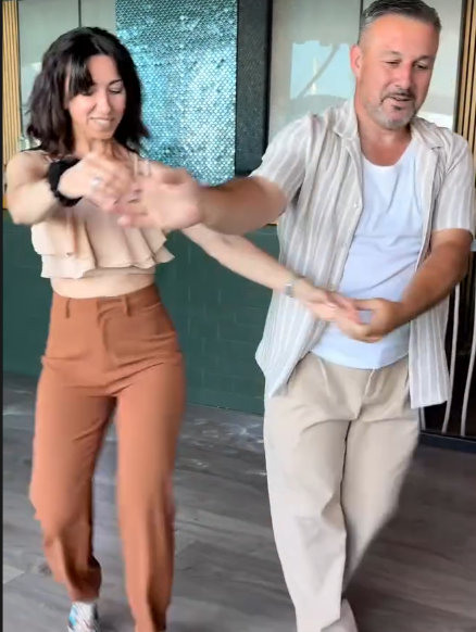 Dos asistentes bailan en pareja junto a los ventanales de Algues Club